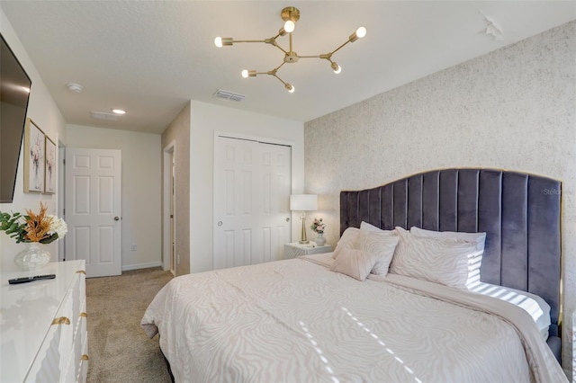 carpeted bedroom with a closet and an inviting chandelier