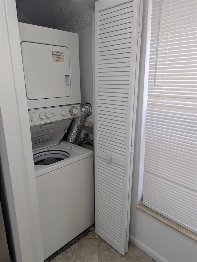 clothes washing area featuring stacked washer and clothes dryer and a textured ceiling