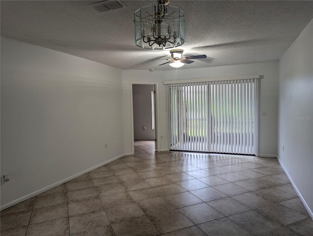 tiled spare room featuring a textured ceiling and ceiling fan with notable chandelier