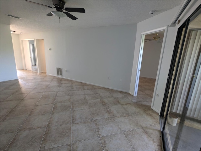 unfurnished bedroom with a closet, a textured ceiling, a walk in closet, light tile patterned floors, and ceiling fan