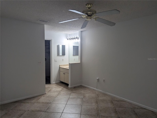 unfurnished bedroom with light tile patterned floors, ensuite bath, a textured ceiling, and ceiling fan