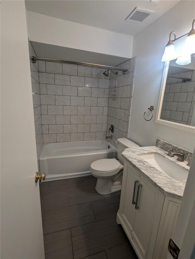 full bathroom featuring tiled shower / bath, vanity, and toilet