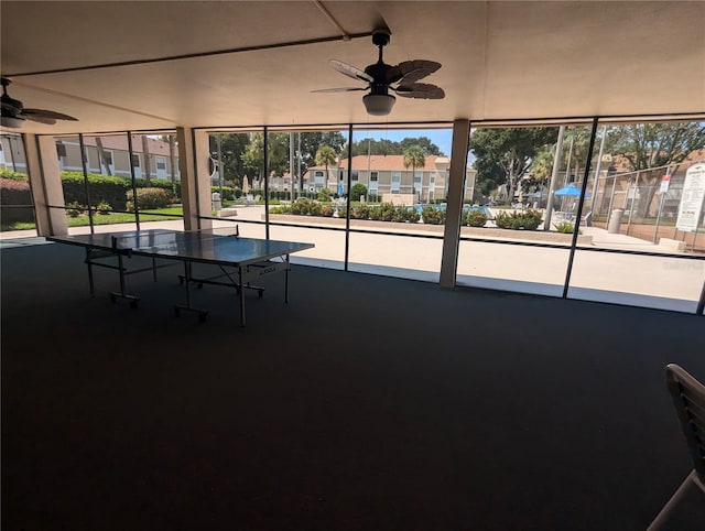 unfurnished sunroom featuring ceiling fan and plenty of natural light