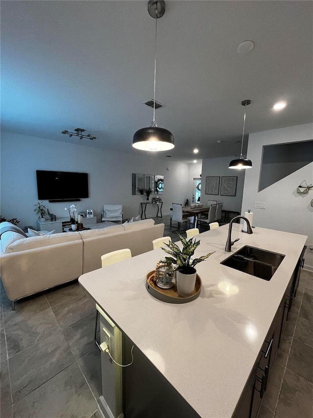 kitchen with hanging light fixtures, a center island with sink, and sink