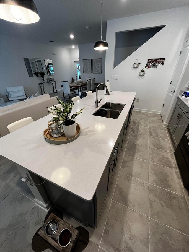 kitchen featuring a center island with sink, a breakfast bar area, sink, and decorative light fixtures