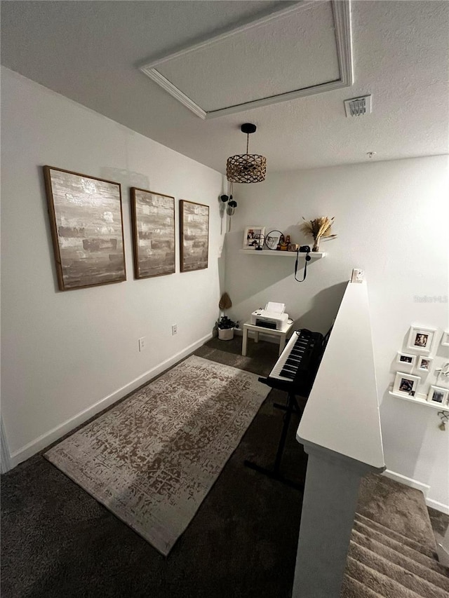 interior space with a textured ceiling and dark carpet