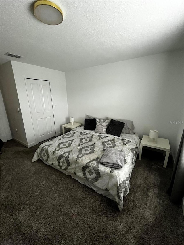 carpeted bedroom featuring a textured ceiling and a closet