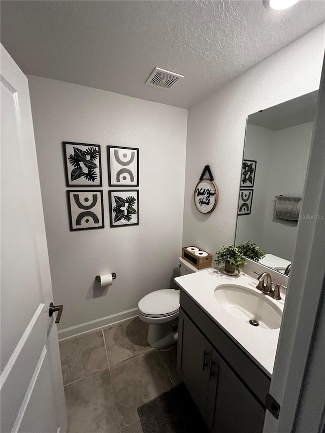 bathroom featuring vanity, toilet, a textured ceiling, and tile patterned floors