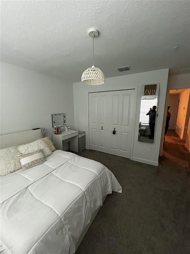 carpeted bedroom featuring a textured ceiling and a closet