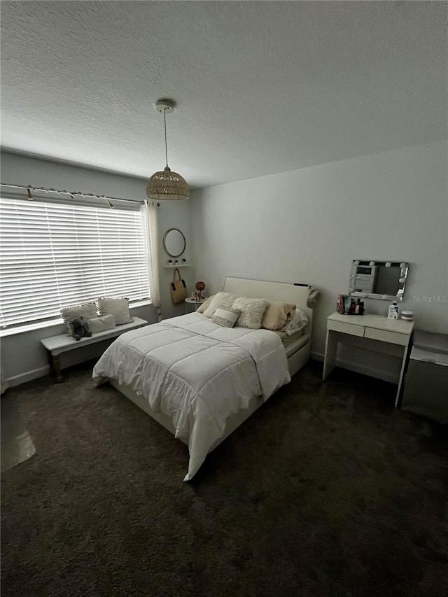 bedroom featuring dark colored carpet and a textured ceiling