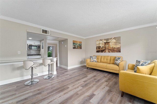 living room with light wood-type flooring, a textured ceiling, and crown molding