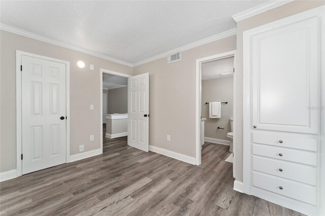 unfurnished bedroom with wood-type flooring, a textured ceiling, ensuite bath, and ornamental molding