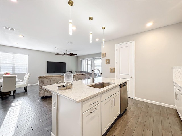 kitchen with ceiling fan, hanging light fixtures, sink, stainless steel dishwasher, and a kitchen island with sink