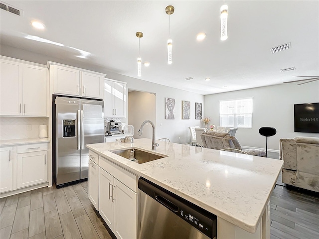 kitchen featuring hanging light fixtures, sink, light hardwood / wood-style flooring, white cabinetry, and stainless steel appliances