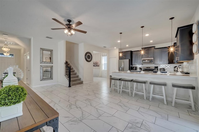 kitchen featuring ceiling fan, pendant lighting, kitchen peninsula, stainless steel appliances, and decorative backsplash