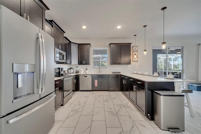 kitchen with appliances with stainless steel finishes, plenty of natural light, a breakfast bar, and decorative light fixtures