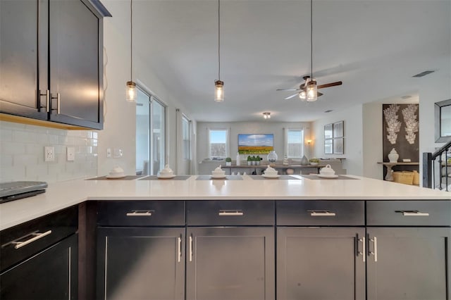 kitchen with gray cabinetry, backsplash, kitchen peninsula, ceiling fan, and decorative light fixtures