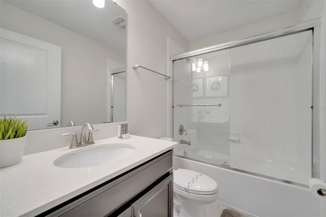 full bathroom with enclosed tub / shower combo, vanity, and toilet