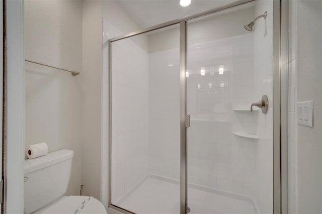 bathroom featuring a shower with shower door and toilet