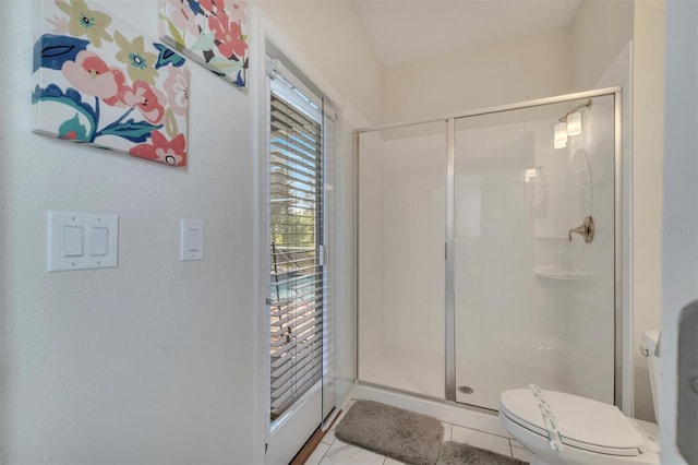 bathroom with tile patterned flooring, toilet, and a shower with door