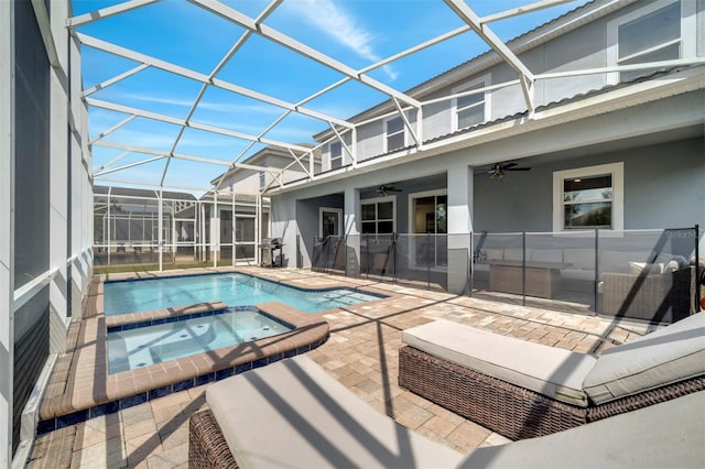 view of swimming pool with glass enclosure, an in ground hot tub, ceiling fan, and a patio