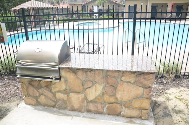 view of patio with area for grilling and a fenced in pool