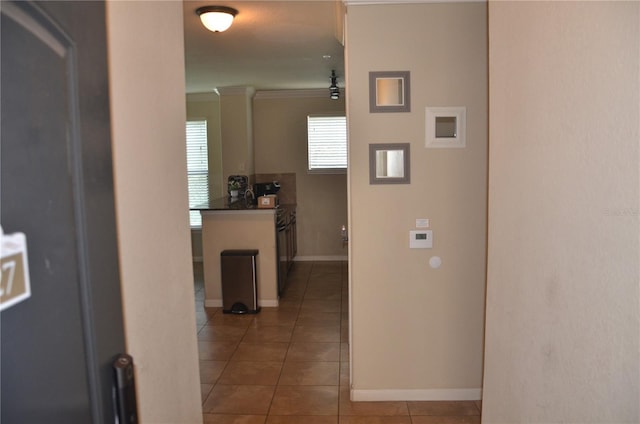 hall with ornamental molding and tile patterned floors