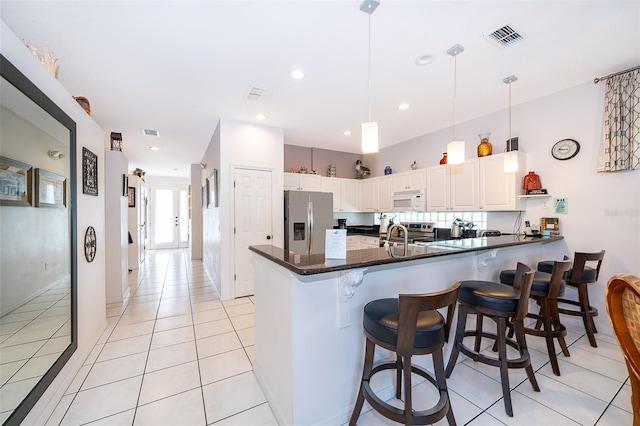 kitchen with white cabinetry, kitchen peninsula, appliances with stainless steel finishes, light tile patterned floors, and decorative light fixtures