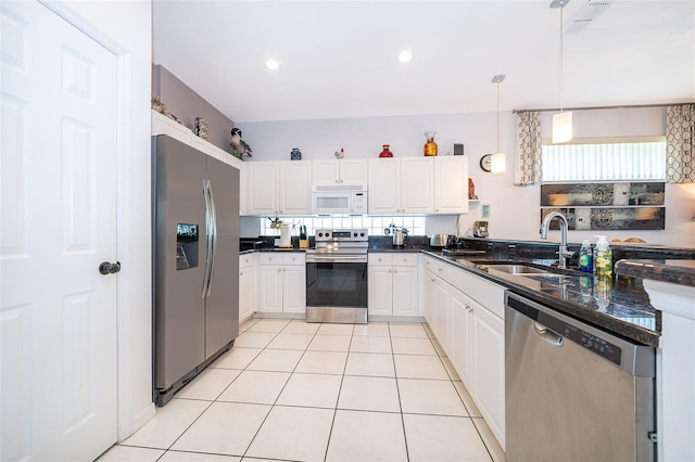 kitchen with pendant lighting, sink, white cabinetry, appliances with stainless steel finishes, and dark stone counters