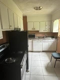 kitchen featuring cream cabinetry, light tile patterned floors, and black electric range oven