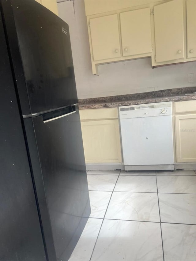 kitchen with black fridge, dishwasher, light tile patterned floors, and cream cabinetry