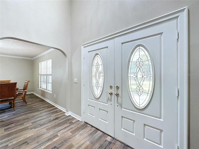 entryway featuring wood-type flooring, crown molding, french doors, and a textured ceiling