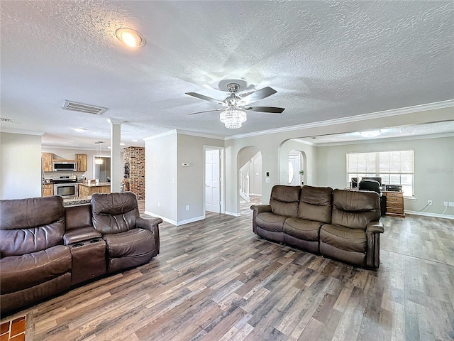 living room with a textured ceiling, ceiling fan, dark hardwood / wood-style flooring, and crown molding