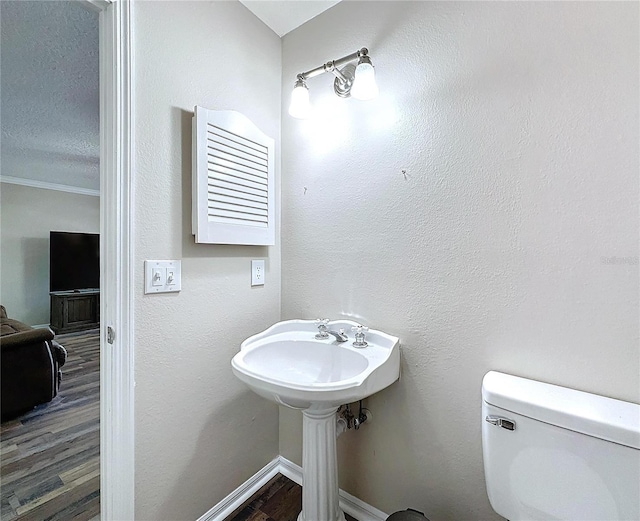 bathroom with toilet, crown molding, a textured ceiling, and hardwood / wood-style flooring