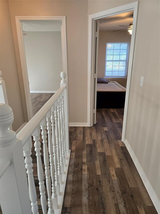 corridor with a textured ceiling and dark hardwood / wood-style flooring