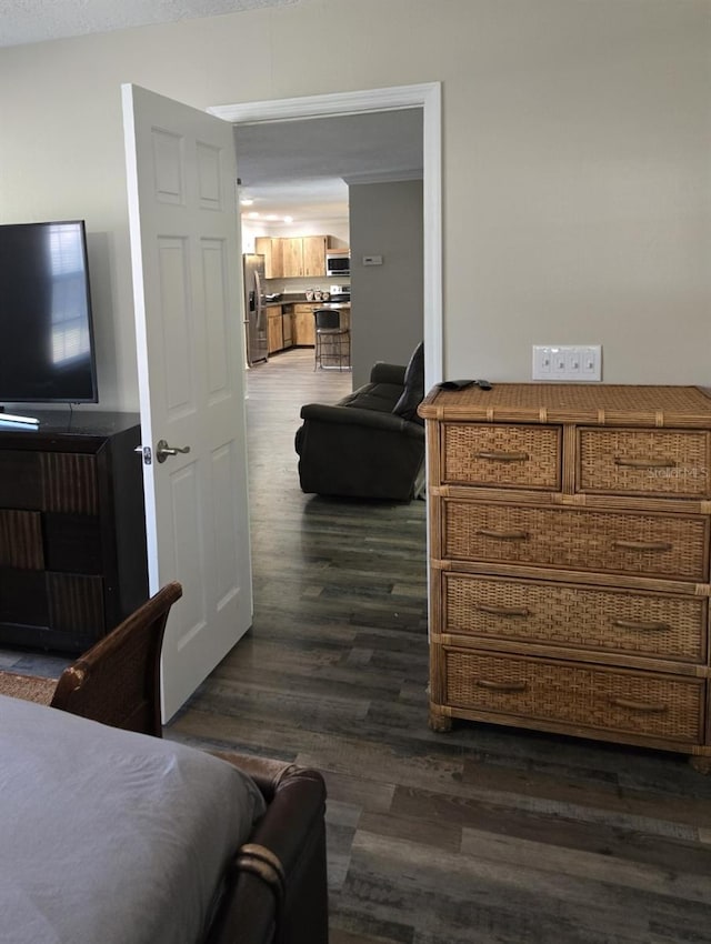 bedroom with dark hardwood / wood-style flooring and stainless steel fridge