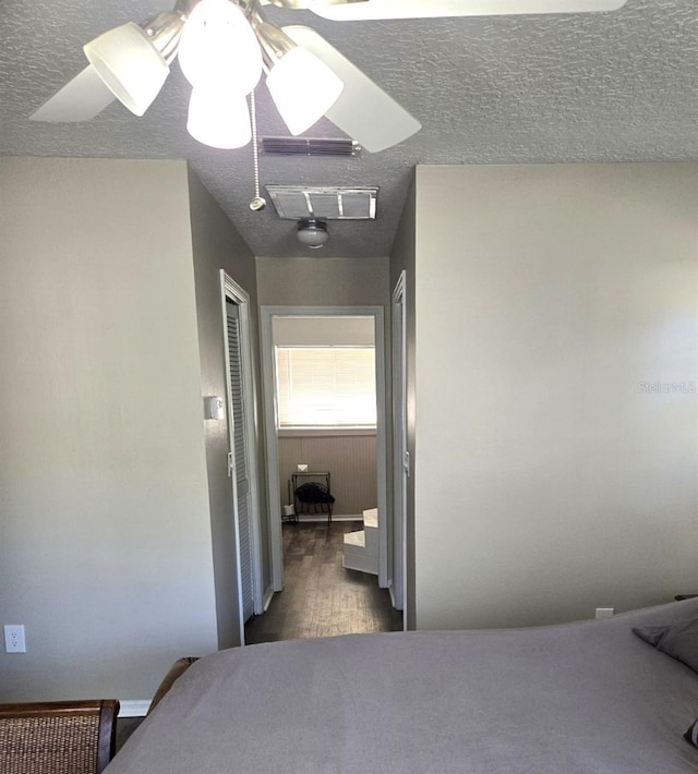 bedroom with ceiling fan, dark wood-type flooring, and a textured ceiling