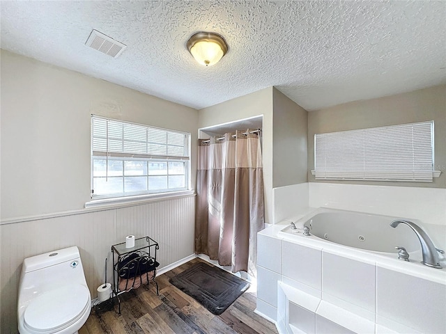 bathroom featuring a textured ceiling, toilet, hardwood / wood-style flooring, and a washtub