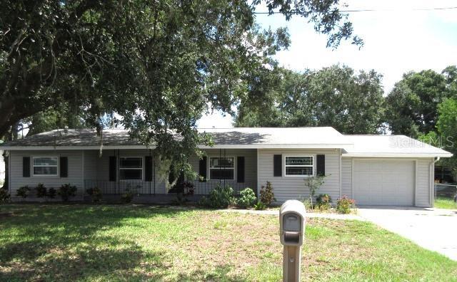 ranch-style house featuring covered porch, driveway, a garage, and a front lawn