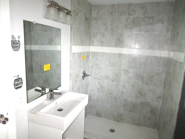 bathroom with a tile shower and vanity