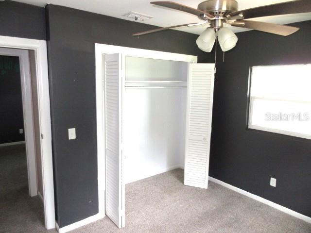 unfurnished bedroom featuring carpet flooring, baseboards, a closet, and ceiling fan