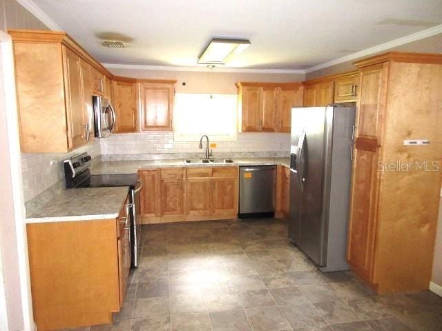 kitchen with light countertops, crown molding, stainless steel appliances, decorative backsplash, and a sink