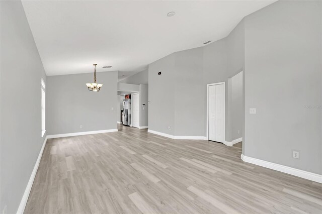 unfurnished living room with a chandelier, light hardwood / wood-style floors, and vaulted ceiling