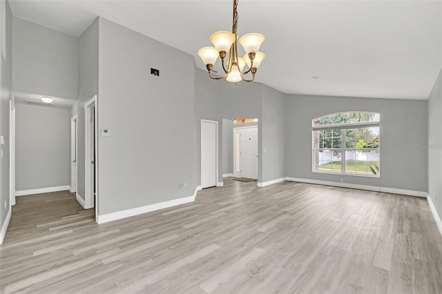 empty room with light wood-type flooring, high vaulted ceiling, and a notable chandelier