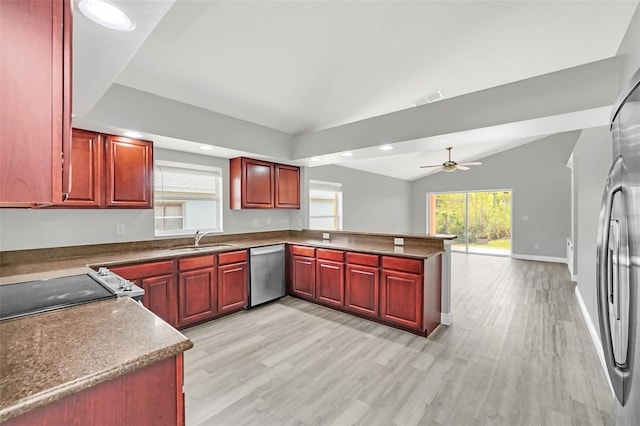 kitchen featuring ceiling fan, kitchen peninsula, appliances with stainless steel finishes, light wood-type flooring, and vaulted ceiling