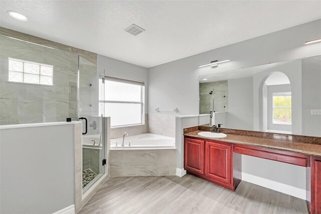 bathroom featuring independent shower and bath, vanity, a textured ceiling, and hardwood / wood-style flooring