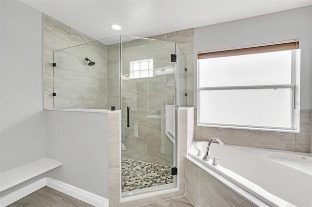 bathroom with shower with separate bathtub and a healthy amount of sunlight