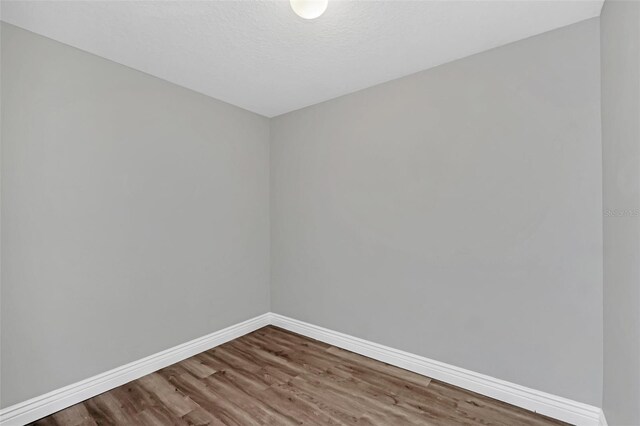 unfurnished room with wood-type flooring and a textured ceiling