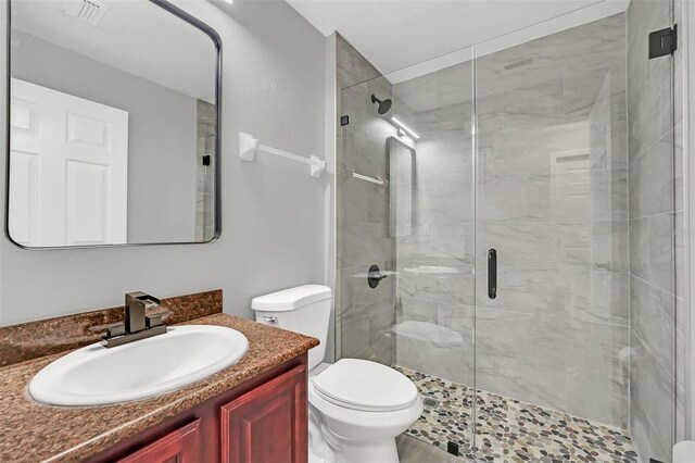 bathroom with vanity, toilet, and a shower with shower door