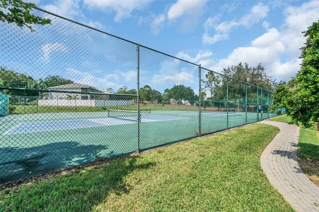 view of tennis court featuring a yard